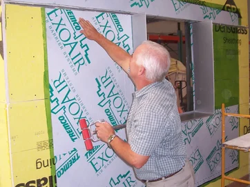 A product consultant applying Tremco ExoAir 110AT Self-Adhered Water and Vapor Barrier Membrane to a test wall assembly.