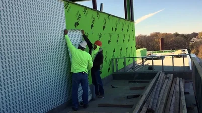 Two skilled professionals install a Tremco non-permeable air barrier on an exterior wall.