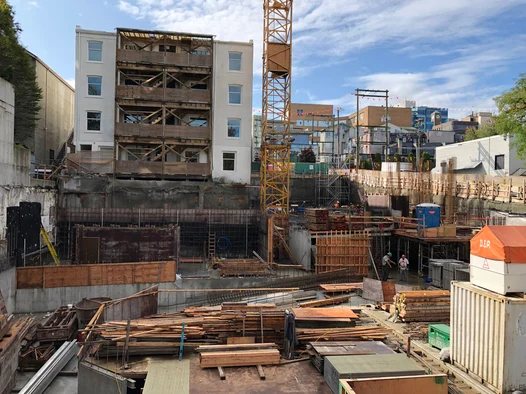 An excavated construction site showcasing the application of Tremco waterproofing membrane on the foundation.