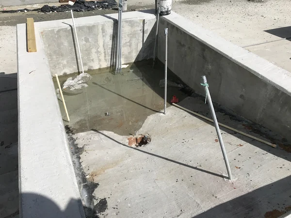 A failed drain design where the drain is improperly located resulting in water ponding on a concrete surface.