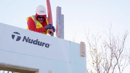 A site worker filling a wall constructed from Nudura ICF blocks with concrete.