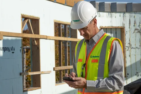 A construction site supervisor ordering new building materials from a mobile phone.