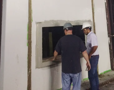 Two workers inspecting a non-combustible building assembly for NFPA 285 compliance.