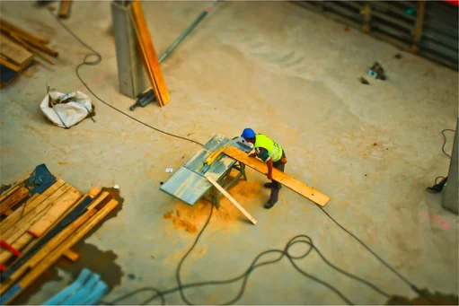 A professional cutting a wooden plank to meet ASTM E1886 and ASTM E1996 size requirements prior to attaching to a wall framing assembly.