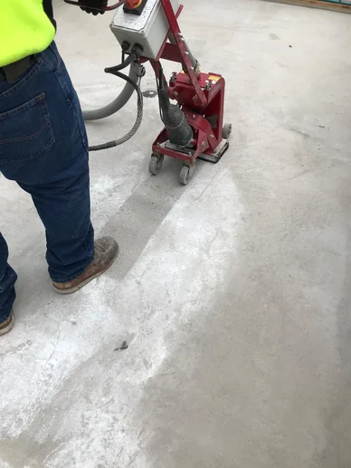 A worker scarifying a concrete floor in preparation to repitch the flooring before waterproofing.