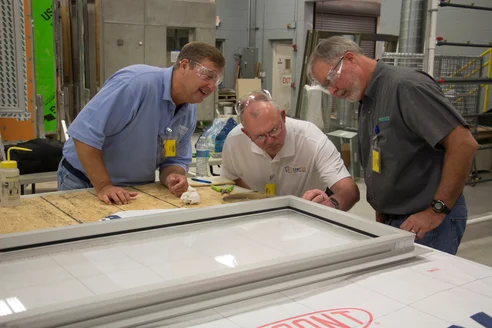 Several building material systems profProfessionals are examining an individual window unit treated with a Tremco air barrier membrane.