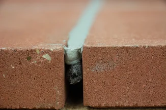 A bead of sealant shown filling the gap between two brick substrates.