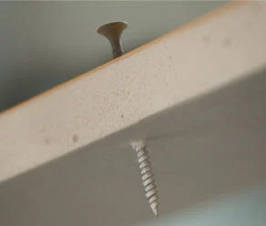 A detailed shot capturing a screw piercing through a barrier as a component of the ASTM E331 Standard Test for Water Penetration.