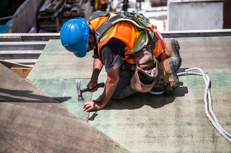 A roof worker shown securing nails into a FORTIFIED roof constructed to be more weather resilient than standard roofing designs.